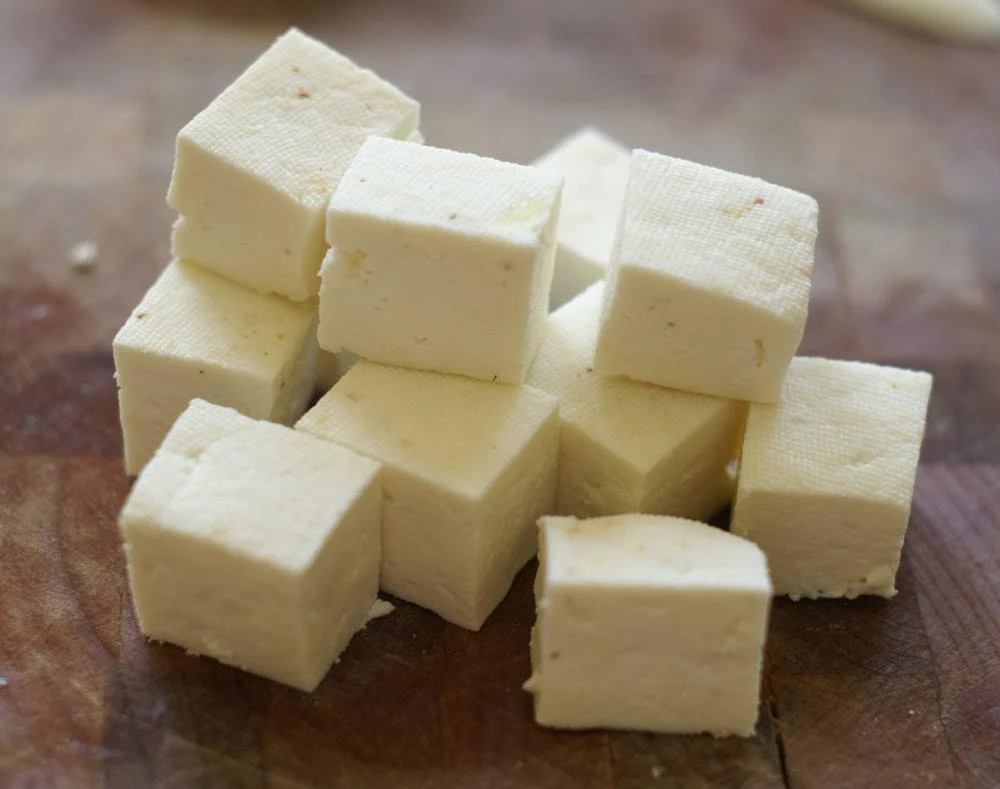 Fresh cow milk paneer cubes on wooden surface